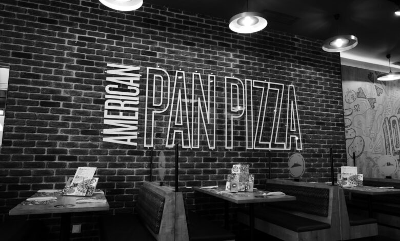 Black and white image of an American pan pizza restaurant with stylish brick wall decor.