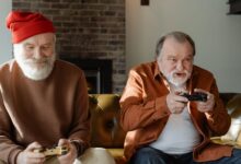 Two elderly men having fun playing video games on the couch.