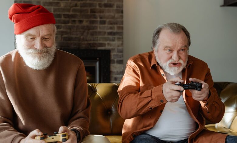 Two elderly men having fun playing video games on the couch.