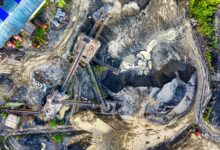 Top-down drone shot of an industrial mining site in Rumpin, West Java, showing machinery and excavation.