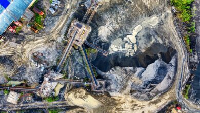 Top-down drone shot of an industrial mining site in Rumpin, West Java, showing machinery and excavation.