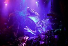 Exciting dinosaur display with vibrant lighting in an entertainment park.