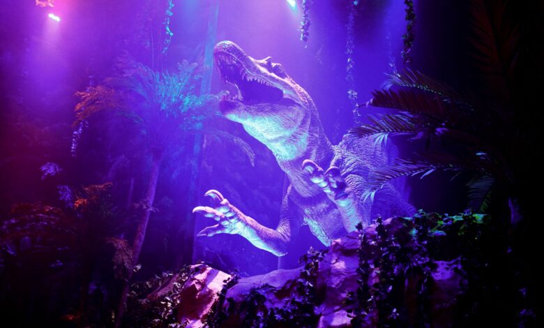 Exciting dinosaur display with vibrant lighting in an entertainment park.