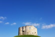 Clifford's Tower in York, England, against a vivid blue sky on a sunny day.