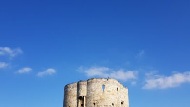 Clifford's Tower in York, England, against a vivid blue sky on a sunny day.