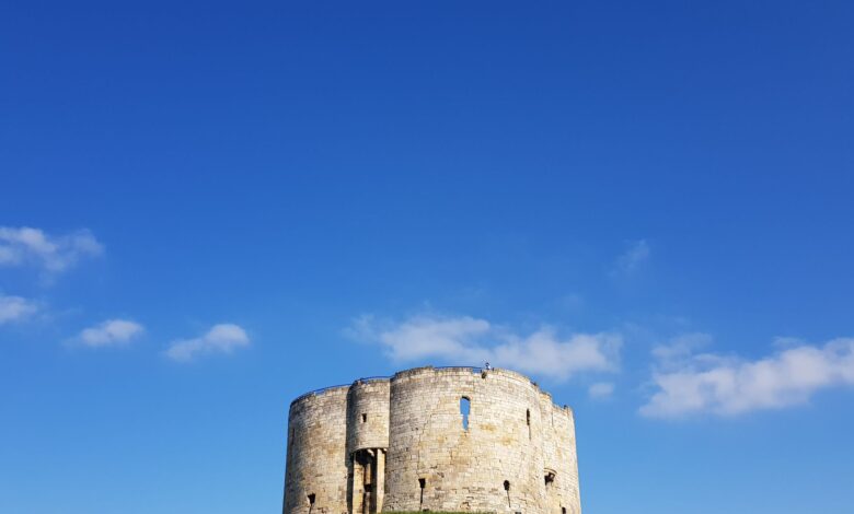 Clifford's Tower in York, England, against a vivid blue sky on a sunny day.