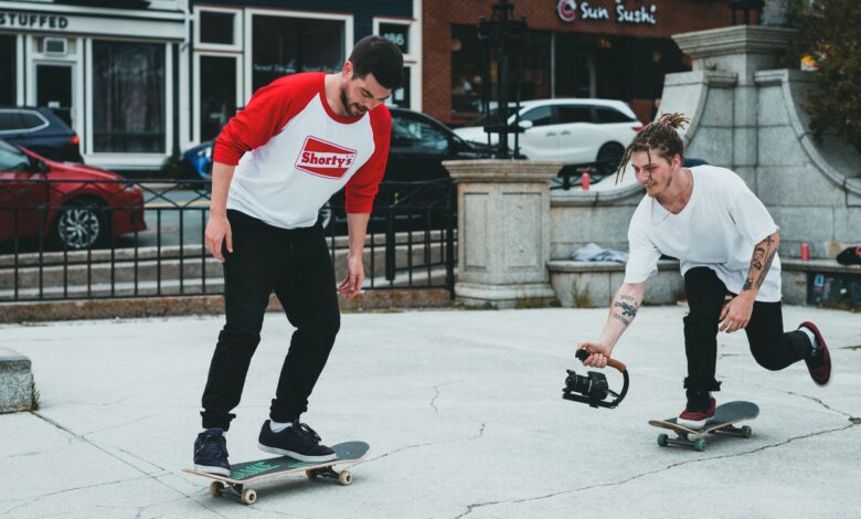Two skateboarders enjoying a casual ride in a vibrant urban area, one holding a camera.