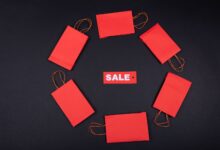 Top view of red paper bags arranged in a circle around a sale tag on a black background.