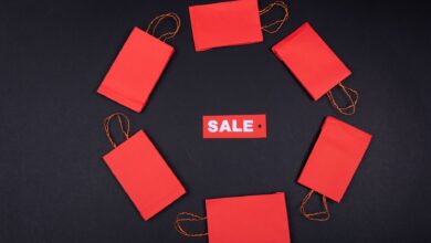 Top view of red paper bags arranged in a circle around a sale tag on a black background.