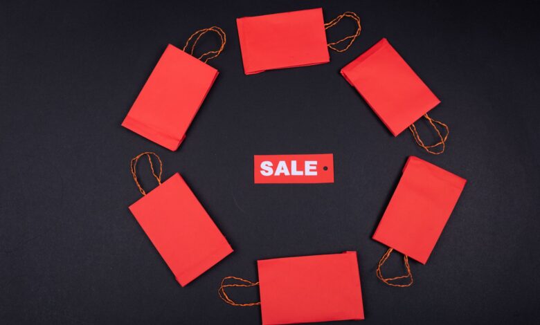 Top view of red paper bags arranged in a circle around a sale tag on a black background.