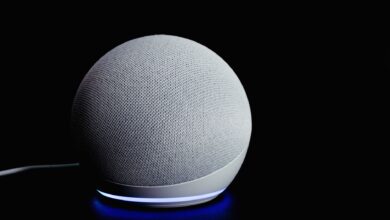 Modern smart speaker device with illuminated ring, featured on a dark background.