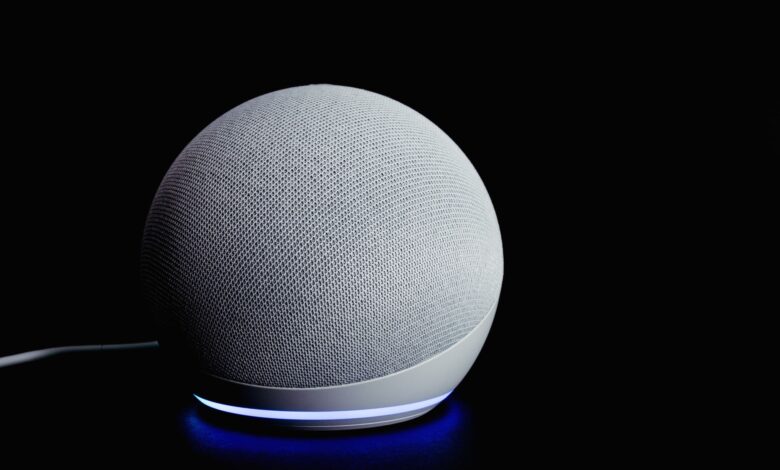 Modern smart speaker device with illuminated ring, featured on a dark background.