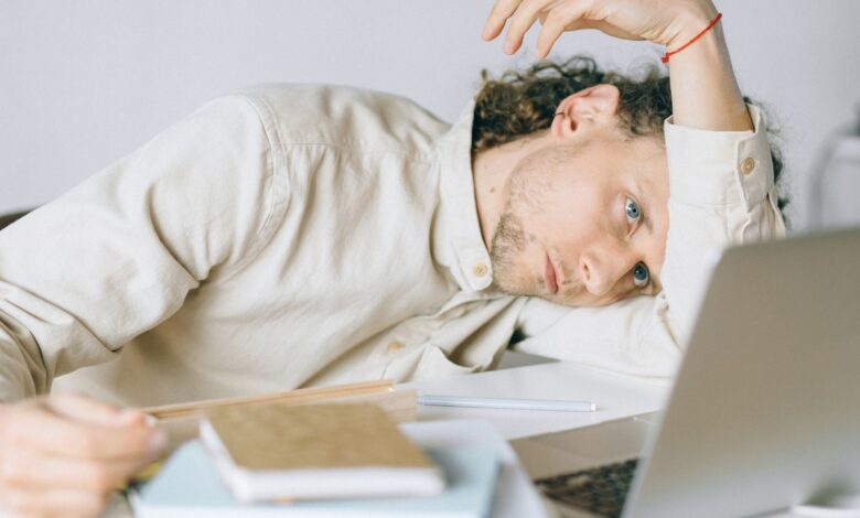 A tired Caucasian man at a desk, showing signs of exhaustion and stress, exemplifying workplace burnout.