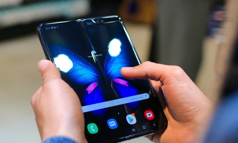 Close-up of hands holding a foldable smartphone showing a butterfly on the screen.