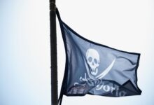 Close-up of a pirate flag with skull waving against the sky.