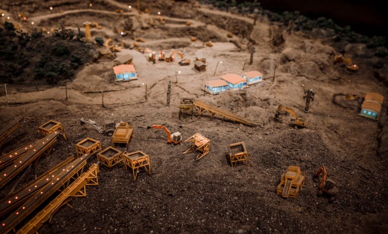 Close-up of a detailed miniature construction site showcasing a quarry with machinery and structures.