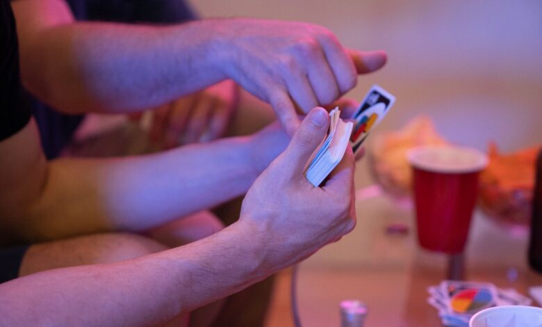 Close-up of hands playing Uno during a friendly indoor game night.