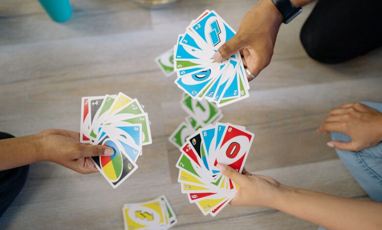 A group of friends enjoying a game of Uno, showcasing colorful cards and hands.