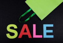 Bright sale text with green shopping bag on black background, perfect for promotions.