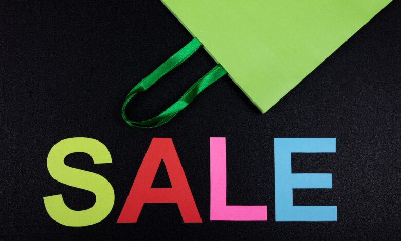 Bright sale text with green shopping bag on black background, perfect for promotions.
