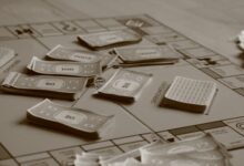 Close-up of board game with play money in sepia tone, focusing on strategic play.