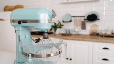 A close-up of a blue stand mixer in a sleek, modern kitchen setting.