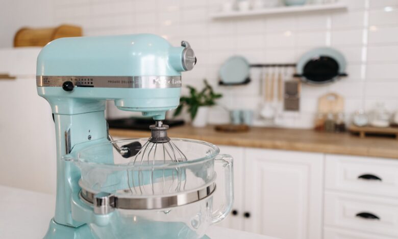 A close-up of a blue stand mixer in a sleek, modern kitchen setting.