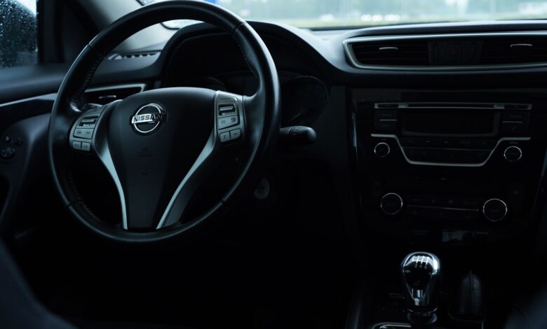 Dark interior view of a Nissan car featuring the steering wheel and dashboard details.