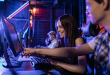 Group of teenagers happily engaged in gaming at a computer setup indoors.