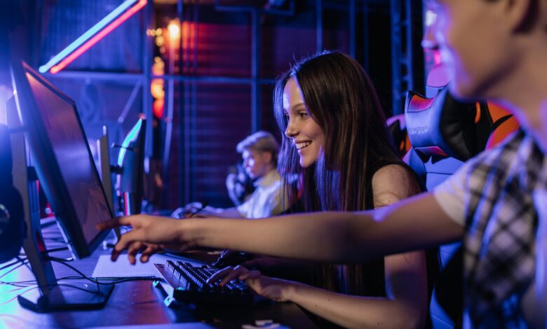 Group of teenagers happily engaged in gaming at a computer setup indoors.