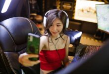A young woman gamer with headphones taking a selfie during a gaming session.