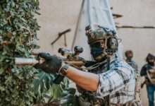 Armed soldier in tactical gear strategizing in an urban setting.