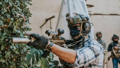 Armed soldier in tactical gear strategizing in an urban setting.