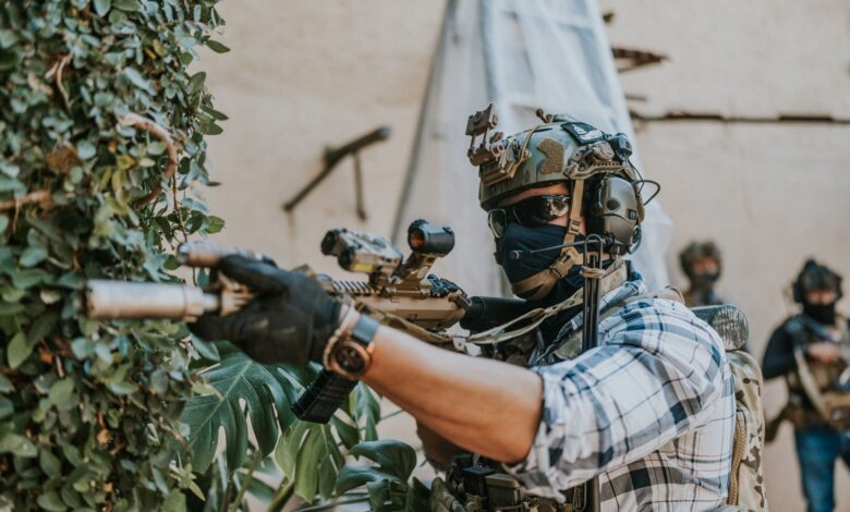 Armed soldier in tactical gear strategizing in an urban setting.