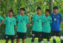 A group of young male soccer players in green jerseys standing outdoors in Myanmar.
