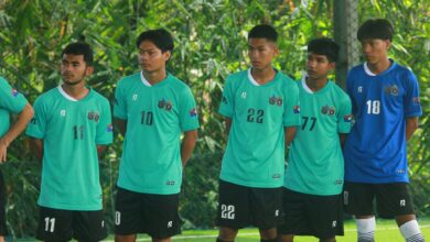 A group of young male soccer players in green jerseys standing outdoors in Myanmar.