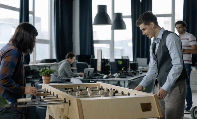 Office workers taking a break to play foosball in a modern startup environment.