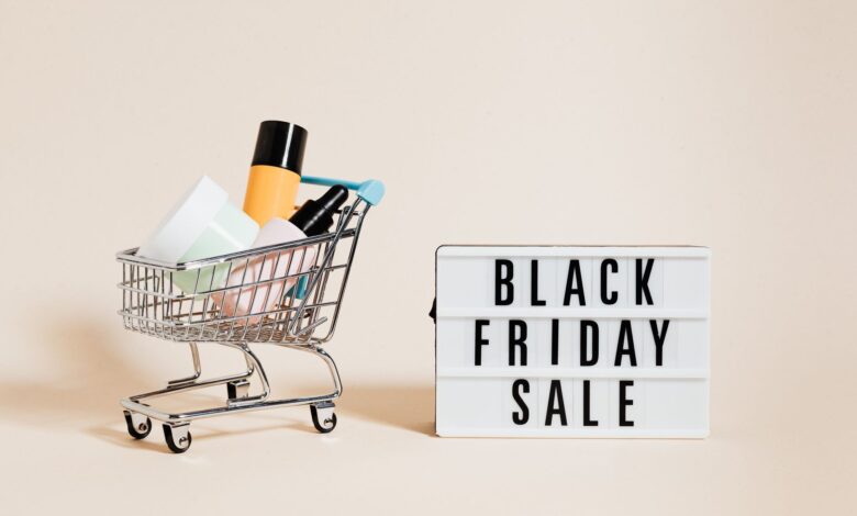 Stylish display of a mini shopping cart and a Black Friday sale sign on a beige background.