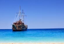 A classic pirate ship anchored near a sandy beach on Zakynthos, Greece.