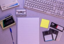 An arrangement of retro office supplies featuring vintage electronics and media on a desk.