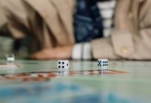 Focused shot of dice in action during a board game with a player in the background.