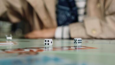 Focused shot of dice in action during a board game with a player in the background.