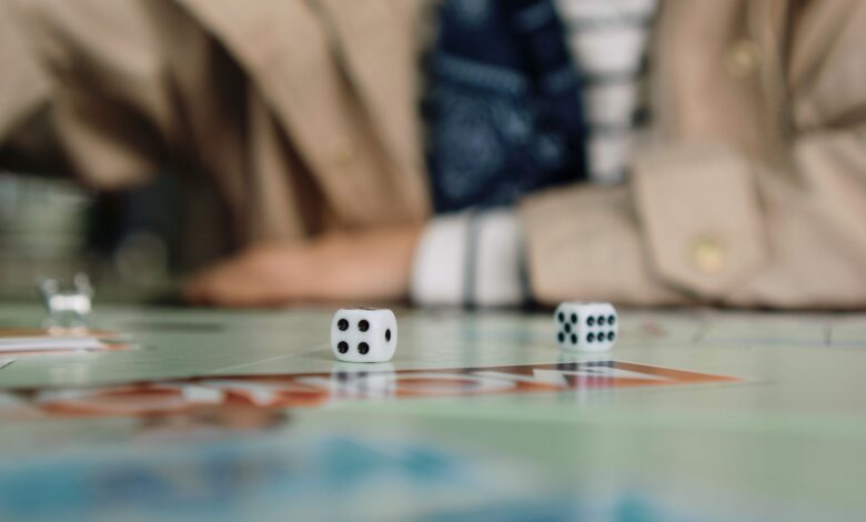 Focused shot of dice in action during a board game with a player in the background.