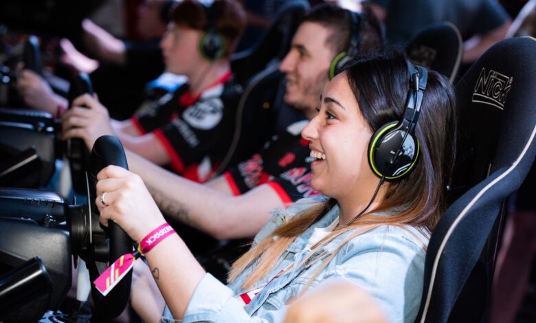 A group of people enjoying an immersive gaming experience at an e-sports center with headphones and steering wheels.
