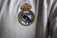 Detailed view of a famous embroidered logo on a white sports jersey fabric.