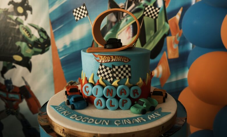 Vibrant Hot Wheels birthday cake with toy cars and a loop track, perfect for a child's party.