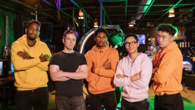 A confident and diverse group of friends standing in an arcade gaming environment.