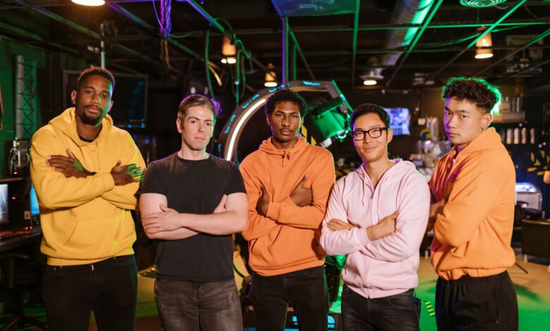 A confident and diverse group of friends standing in an arcade gaming environment.