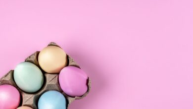 Pastel-colored Easter eggs in a carton on a pink background, perfect for spring themes.