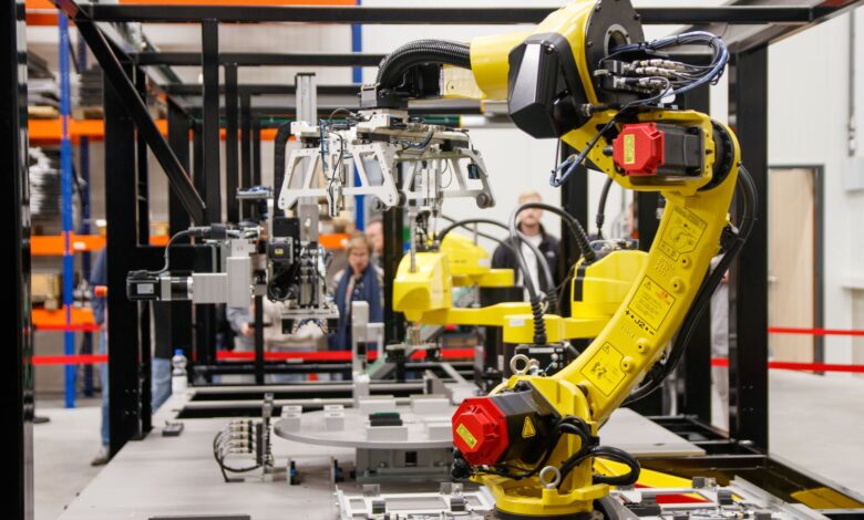 Close-up of a yellow industrial robotic arm in action at a modern manufacturing facility.